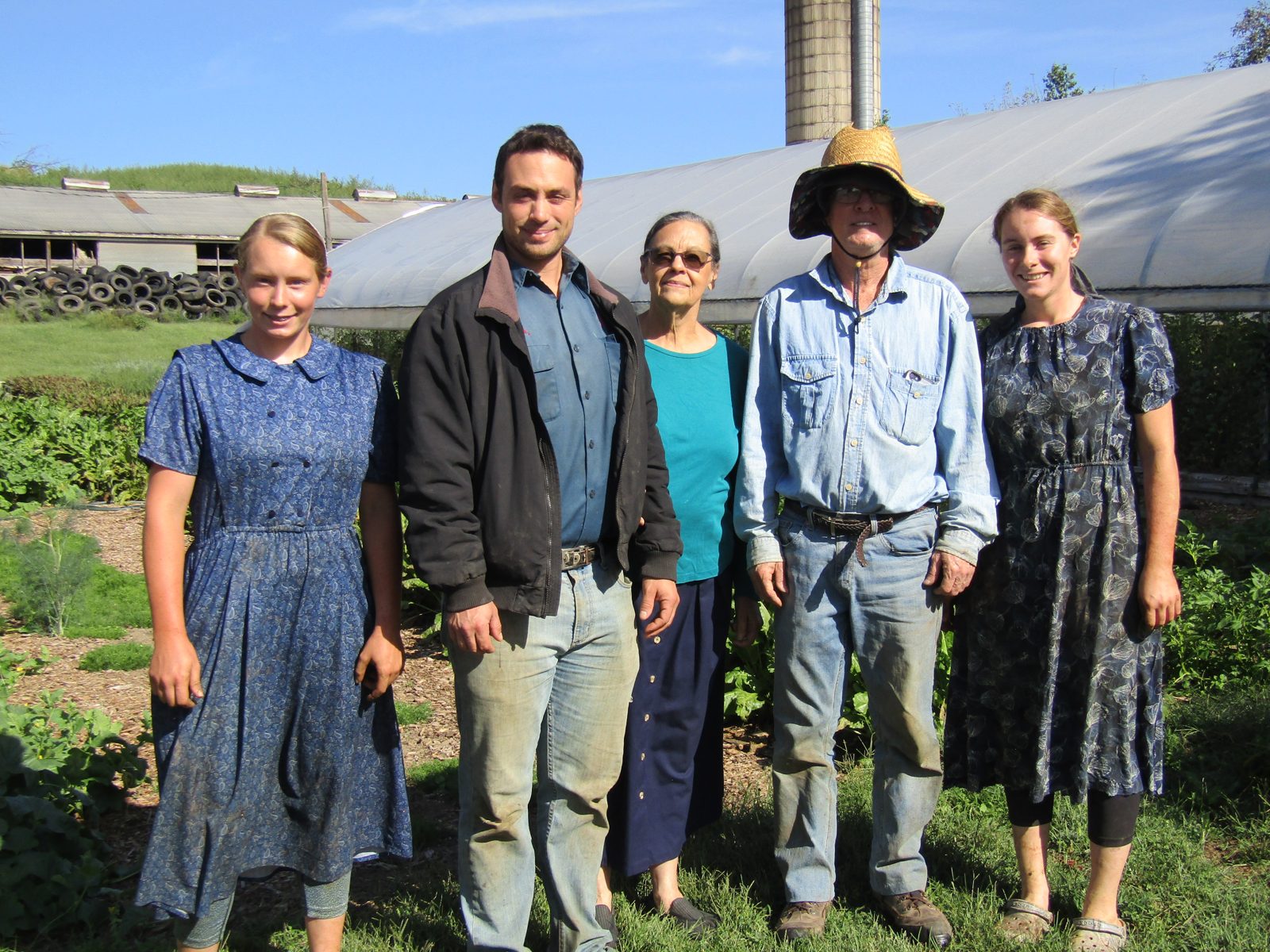 The Wayside Produce Farm family and staff standing together in front of the greenhouse